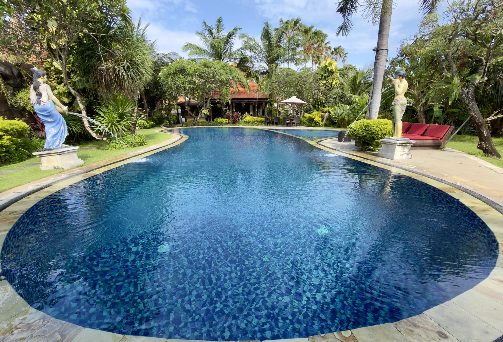 Blue resort-style spa pool set in a garden with palm trees